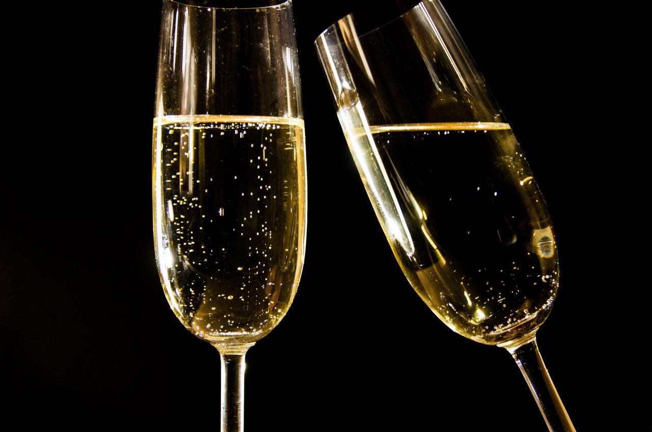 Close-up of champagne glasses with bubbles against a black background, perfect for celebrations.
