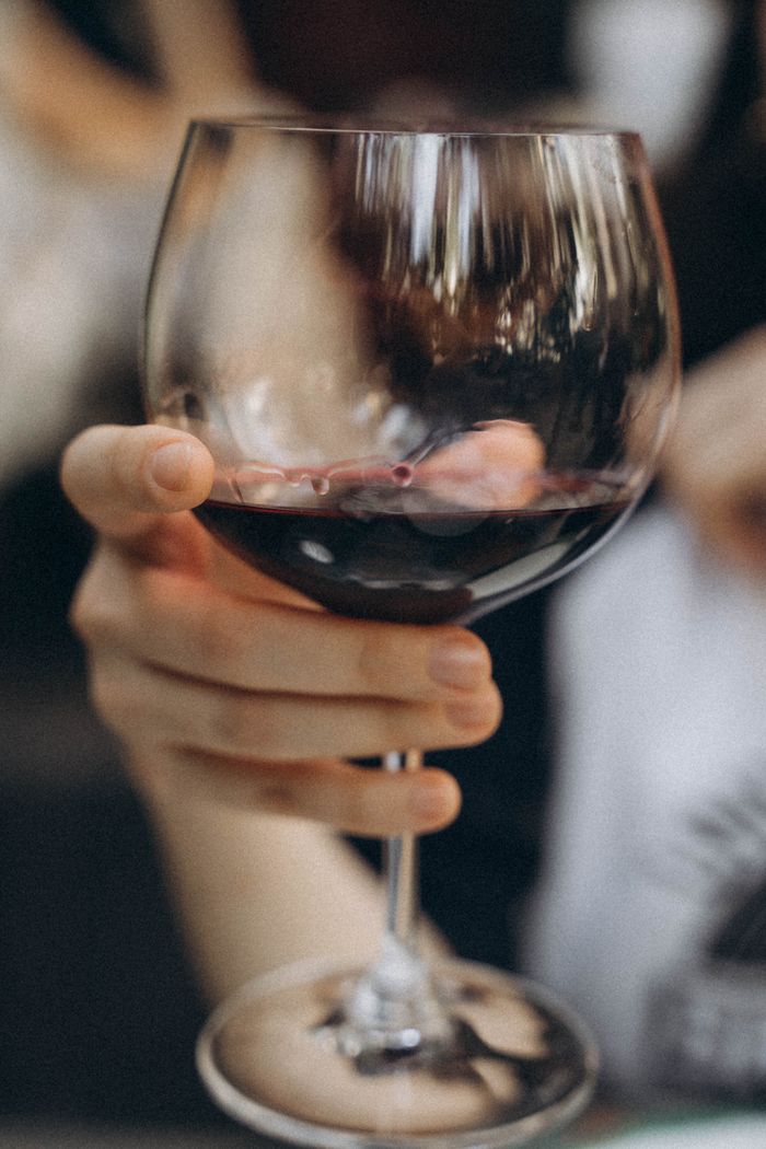 Close-up shot of hand holding a glass of red wine, showcasing elegance and luxury.